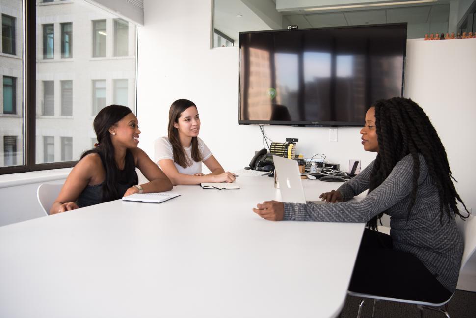 Free Image of Young female co-workers, talking while sitting in meeting room 