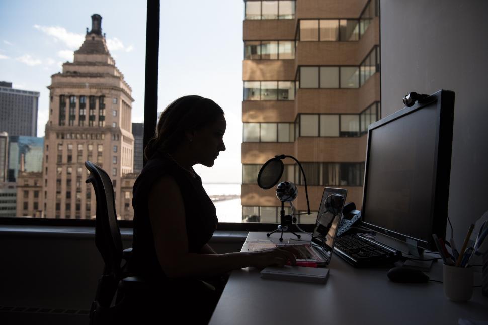Free Image of Woman using computers in office near window 