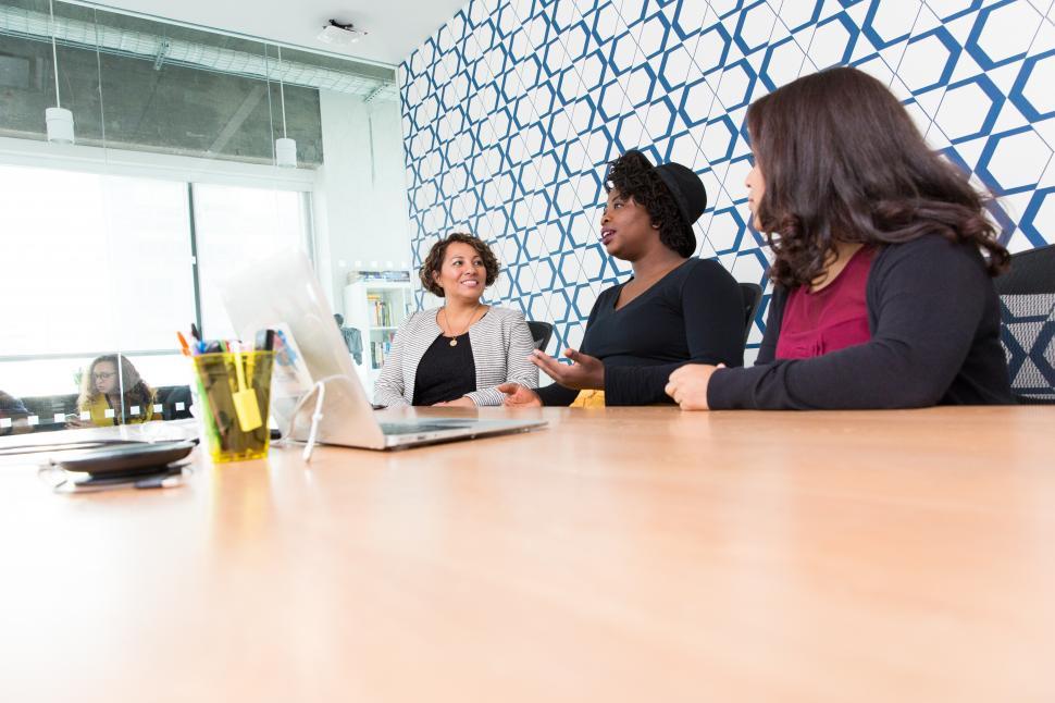 Free Image of Young female co-workers talking in meeting room 
