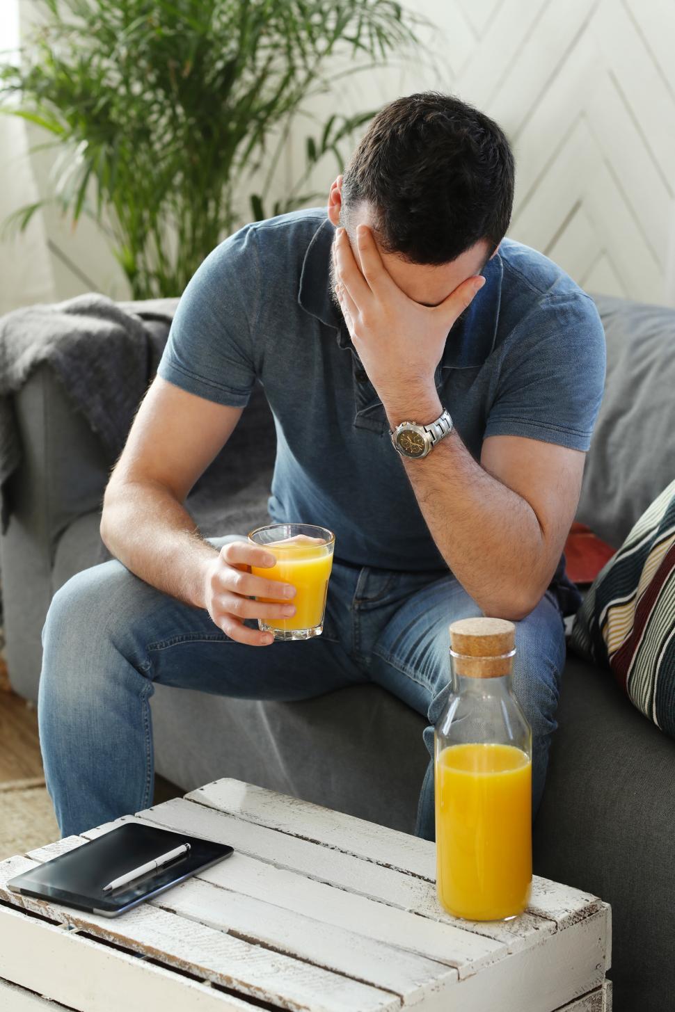 Free Image of Man with orange juice seems troubled 