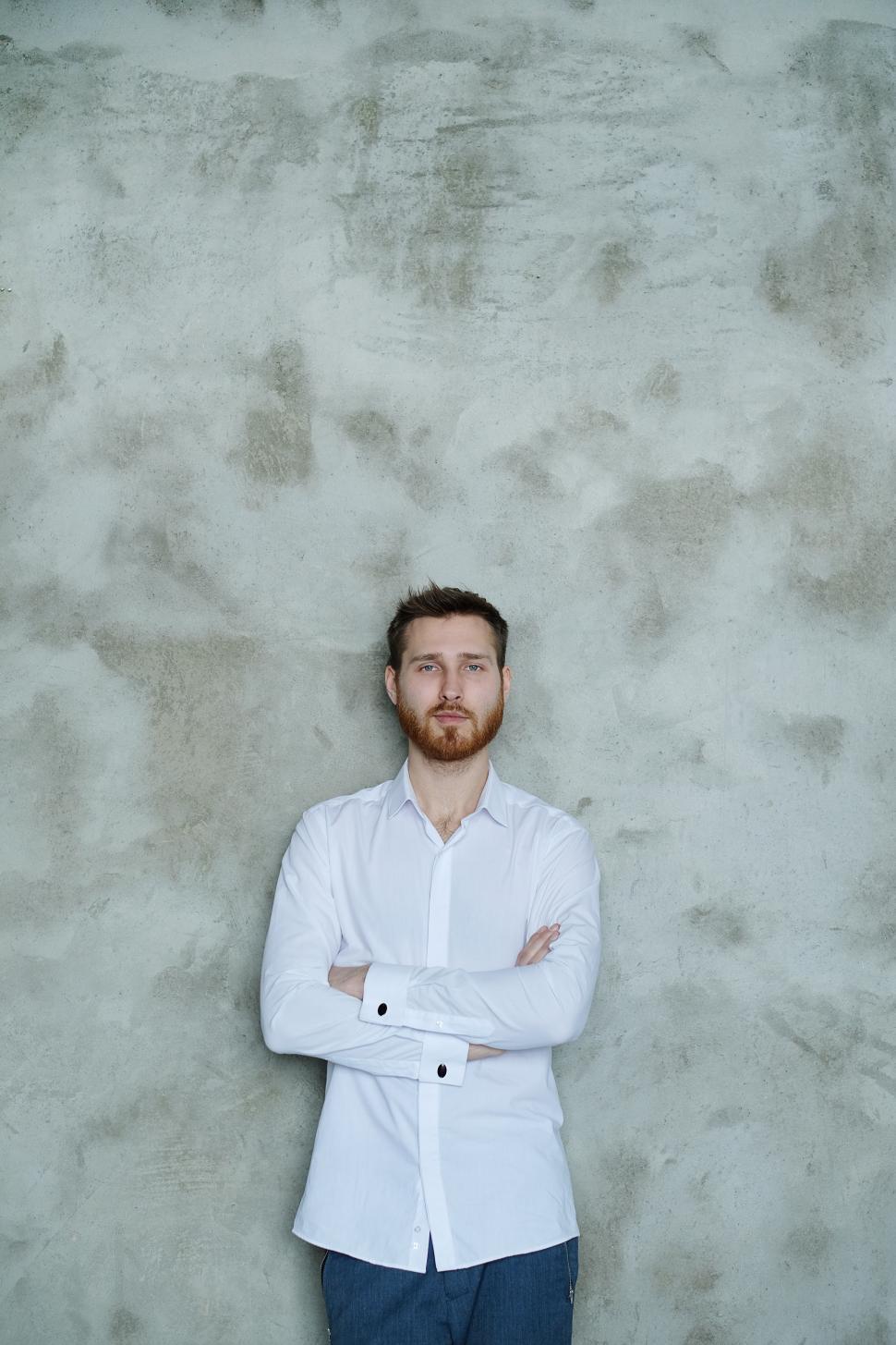 Free Image of Man in white shirt against textured wall 