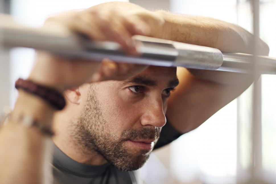 Free Image of Fitness - man resting against weight bar 