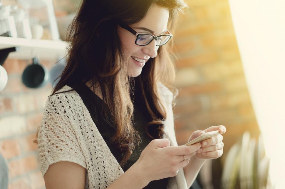 Free Image of Attractive woman in glasses looking at her phone 