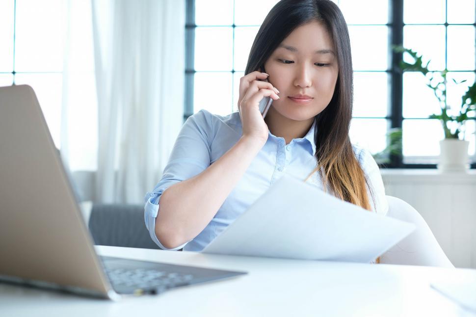 Free Image of Woman on the phone at her desk 