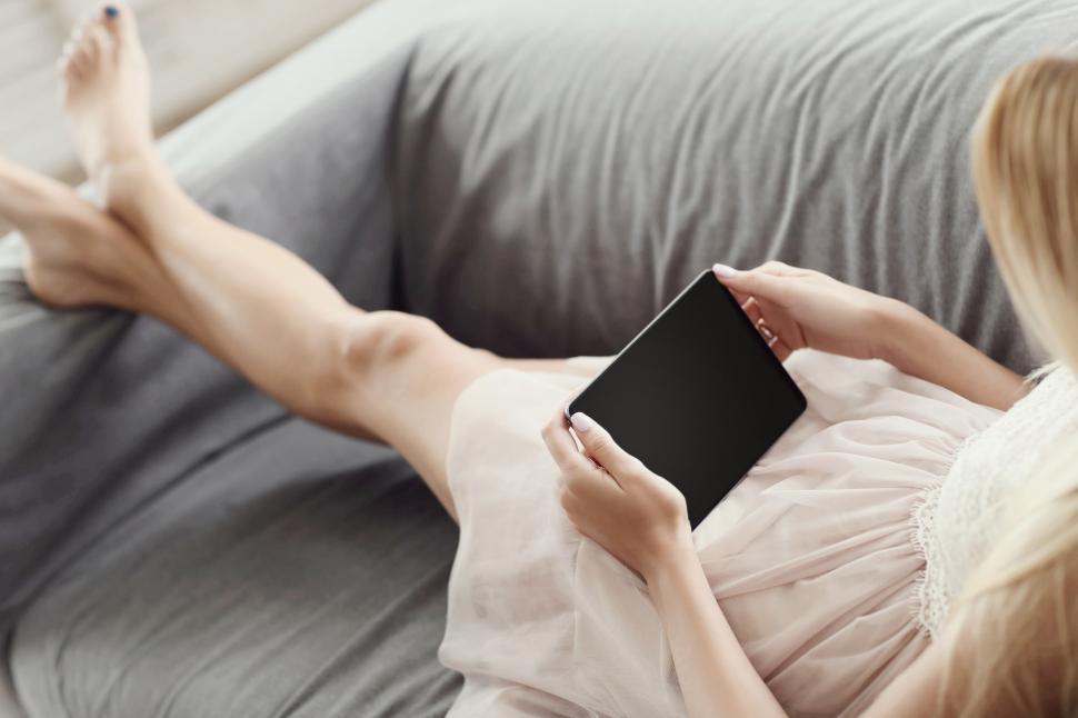 Free Image of Young woman with legs crossed holding tablet device 