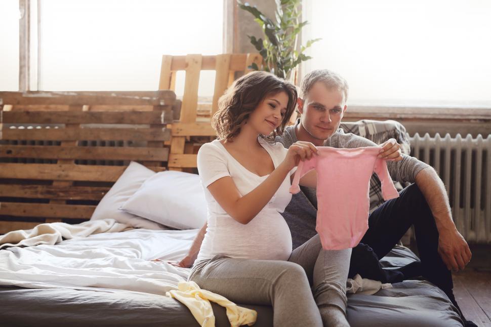 Free Image of Pregnant couple with baby clothes 