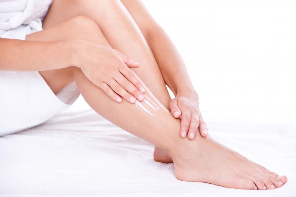 Free Image of Woman applying moisturizing lotion to the legs 
