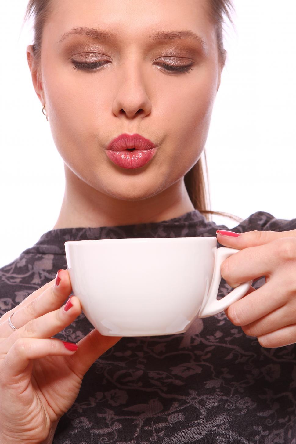 Free Image of Young woman blowing on a cup of hot coffee 