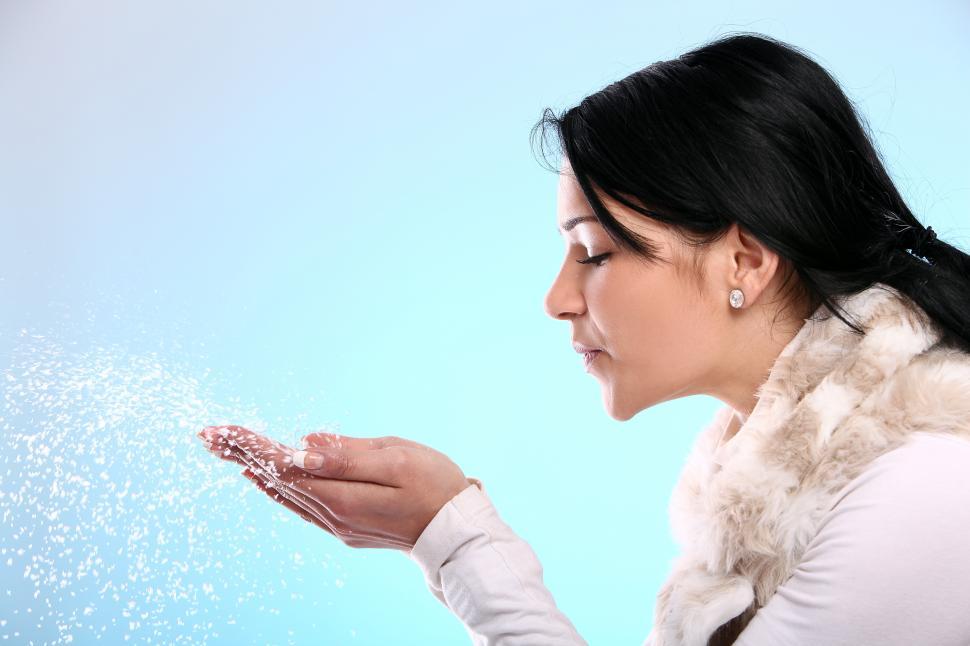 Free Image of Young woman blowing snow 