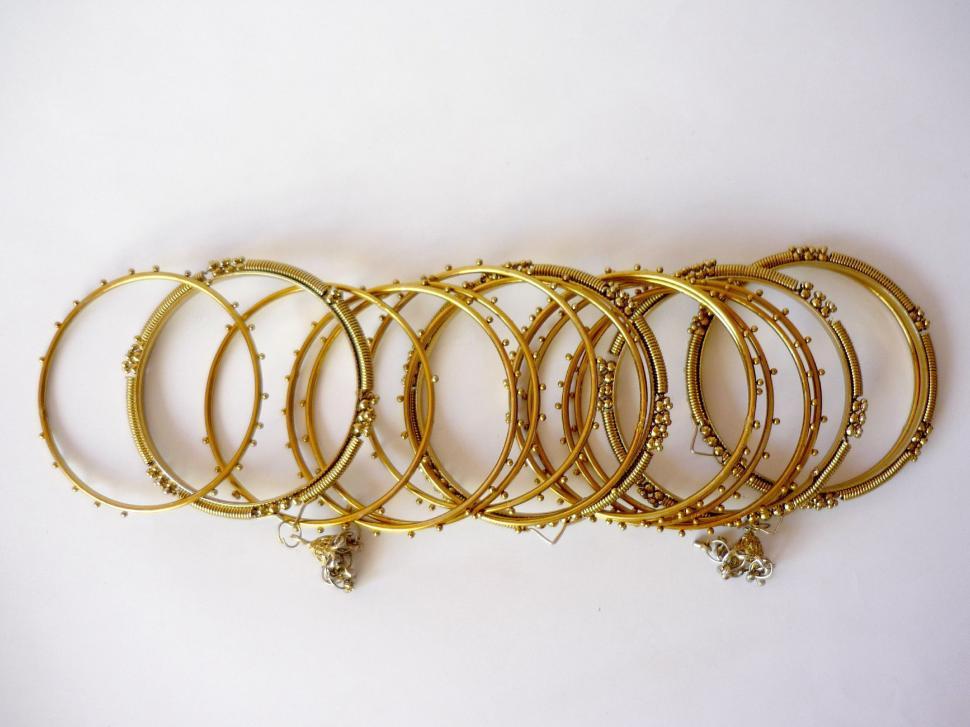 Free Image of Pile of Gold Bracelets on White Table 