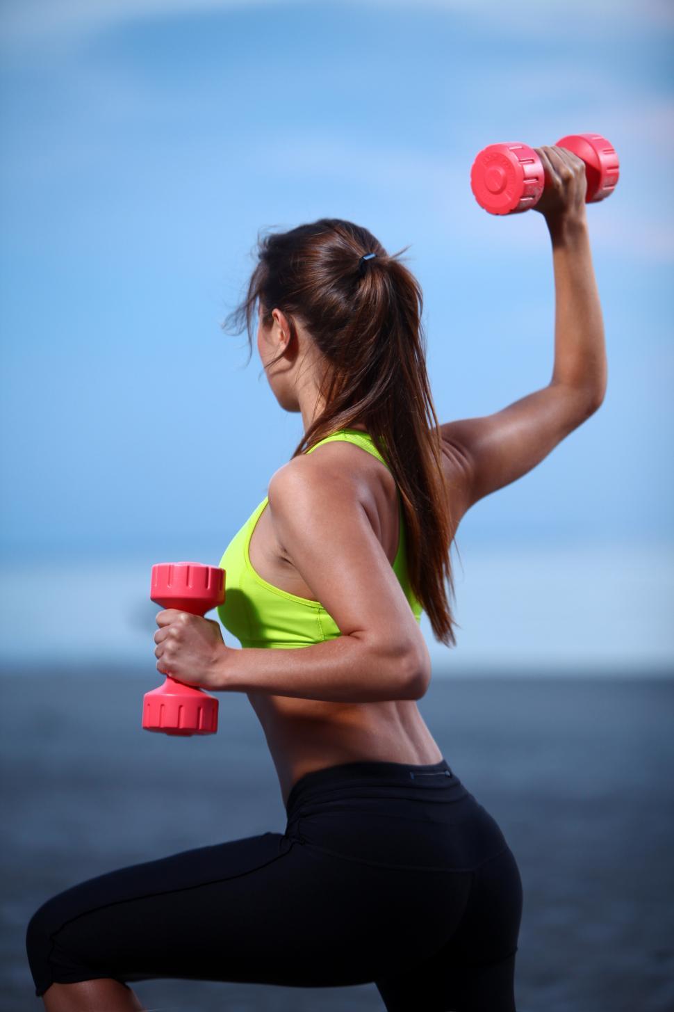 Free Image of Woman doing exercises with dumbbells on the beach 