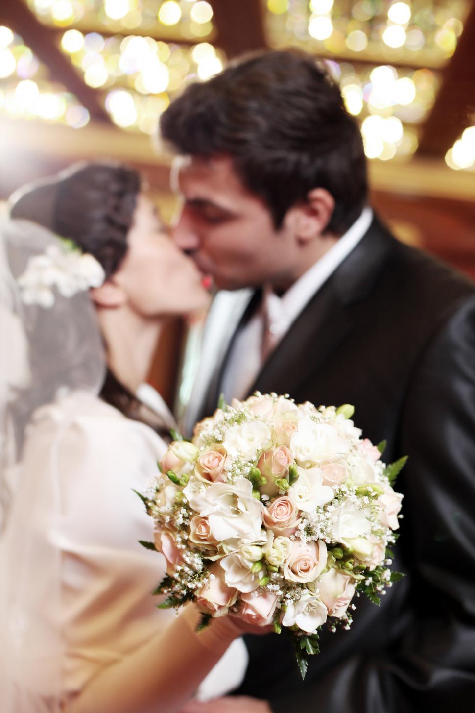 Free Image of Bride and Groom Kiss behind Flowers 