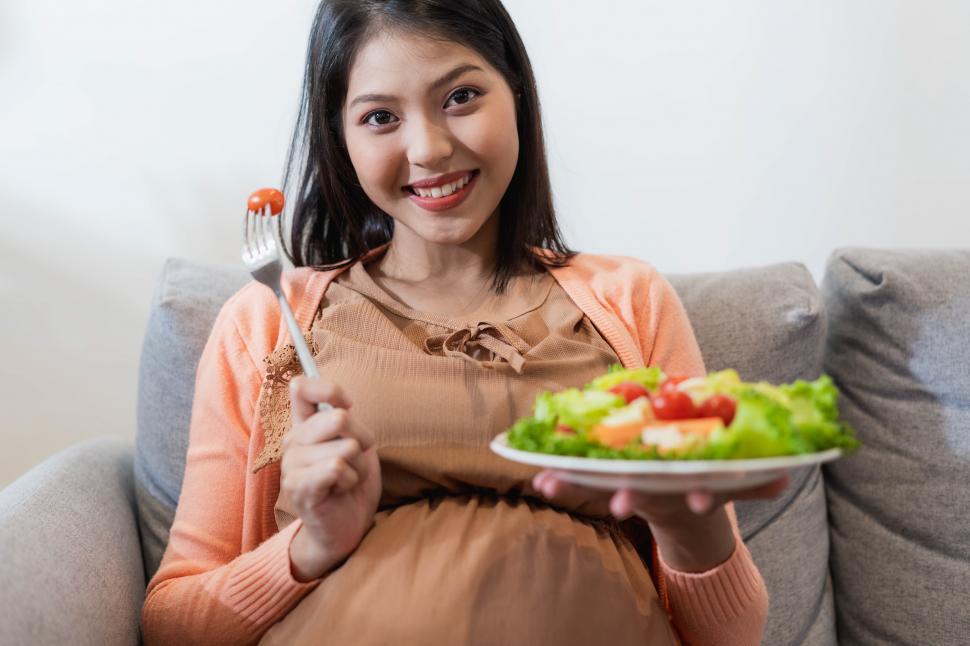 Download Free Stock Photo of Happy pregnant Asian woman sitting and eating natural food 
