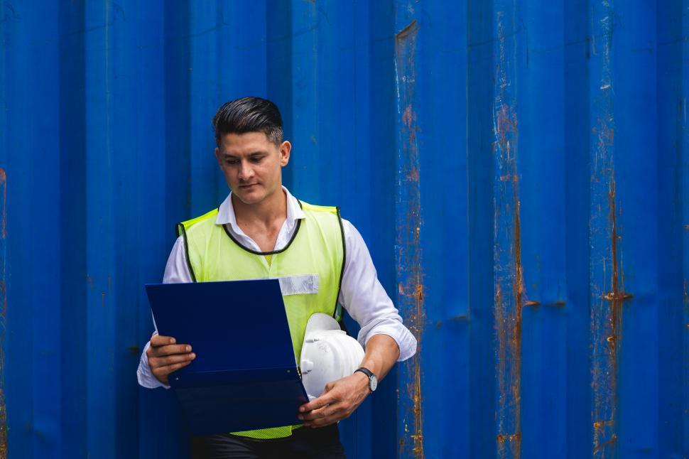 Free Image of Foreman holding document, walking and checking the containers 