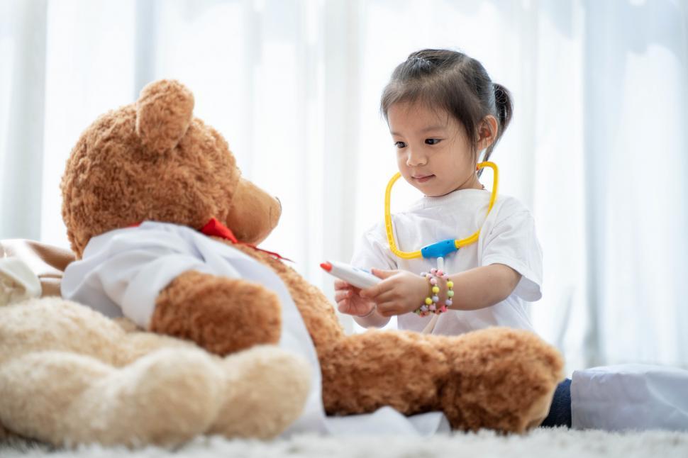 Free Image of A happy asian girl smiling and playing with large teddy bear 