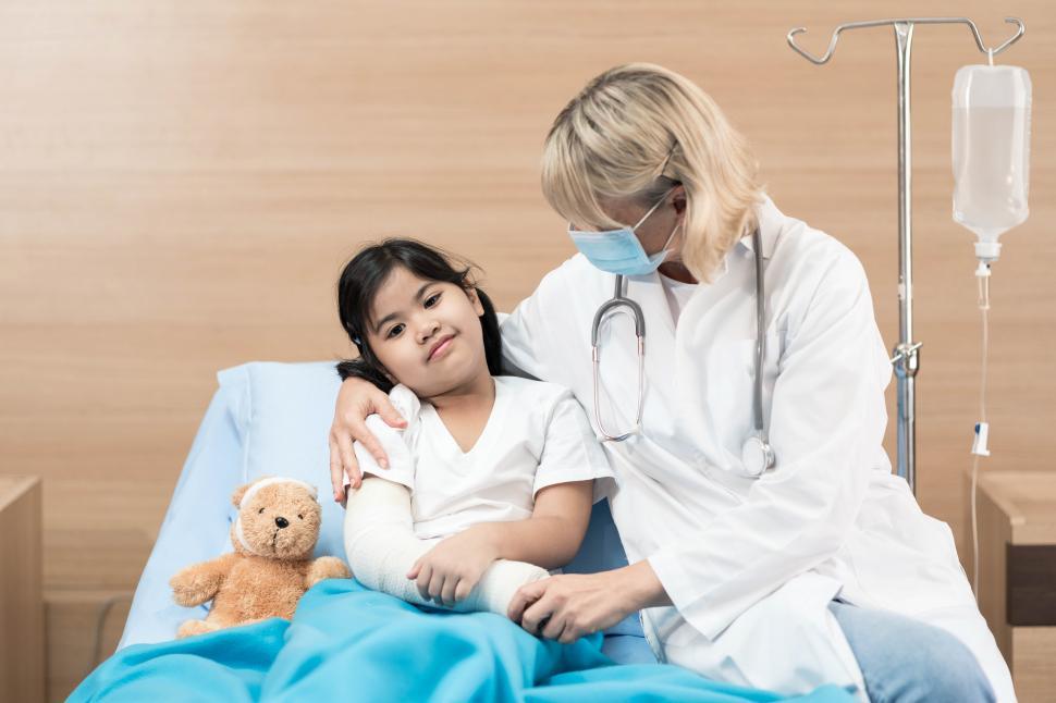 Free Image of Portrait of doctor pediatrician and little girl patient on hospital bed 