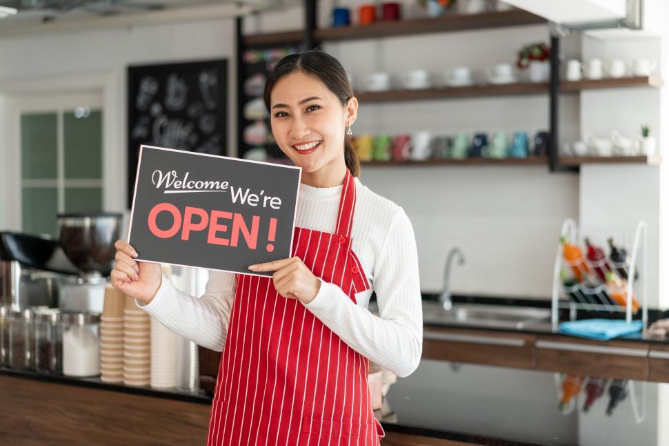 Free Image of Portrait of woman owner standing at her coffee shop with Open sign 