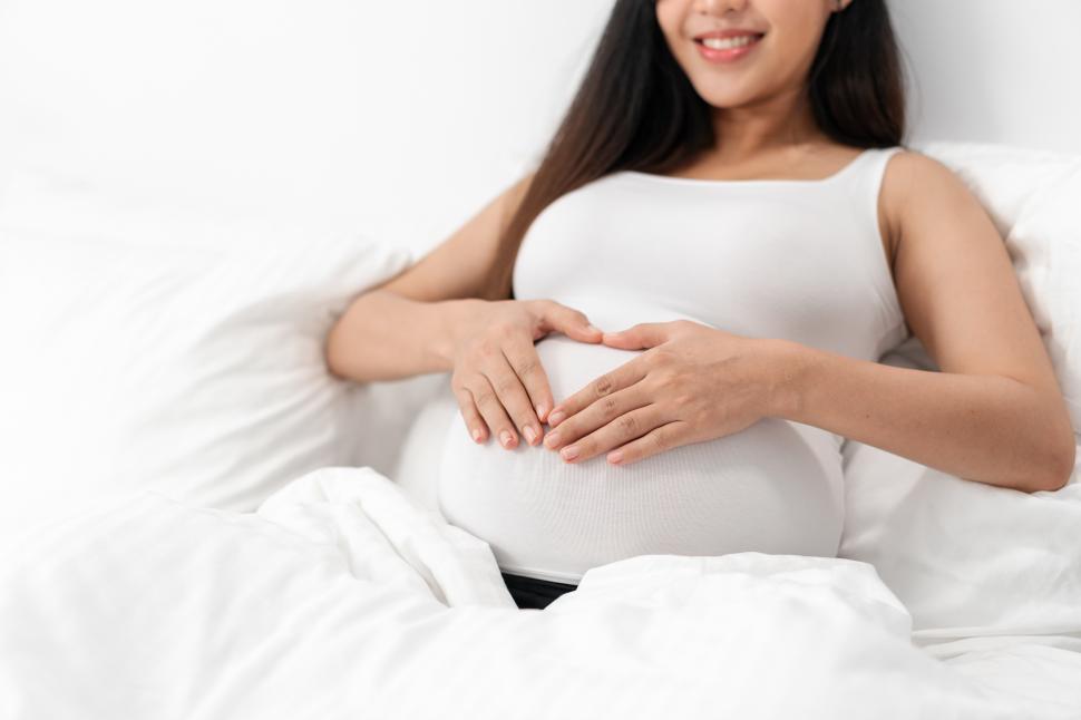 Download Free Stock Photo of Happy pregnant woman is sitting on bed 