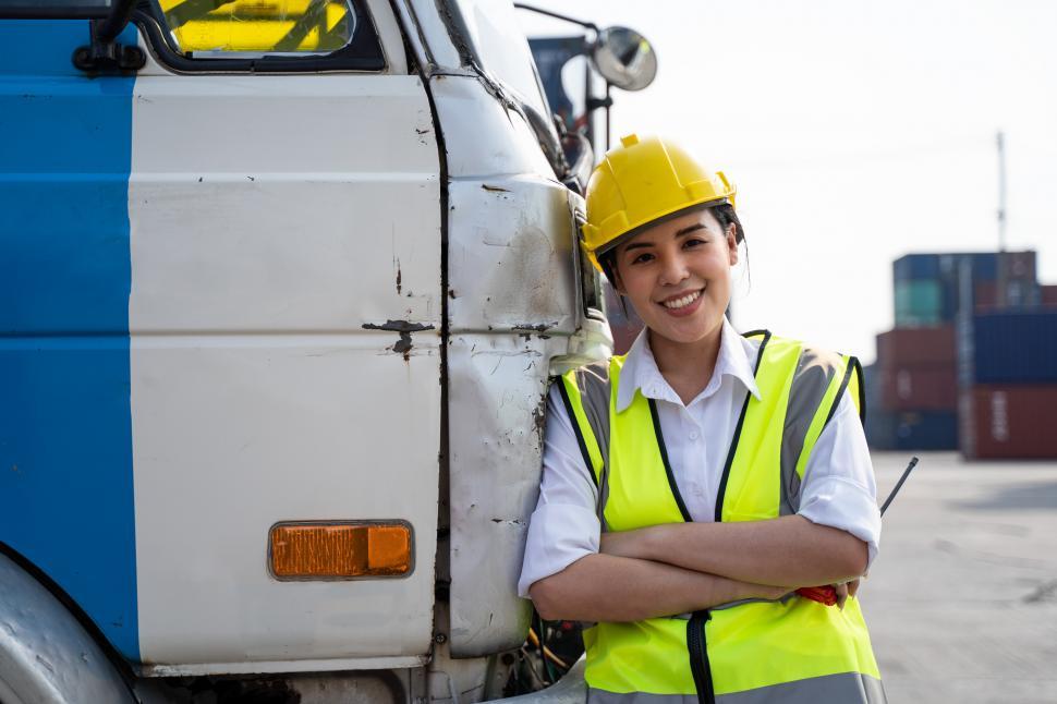Free Image of Truck driver in safety vest leans on her truck 