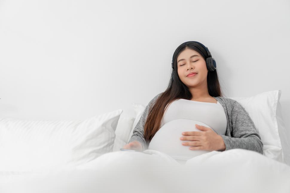 Free Image of Pregnant woman is resting in bed and and touching her belly 