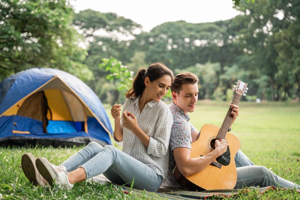 Free Image of Young couple having fun with guitar at campsite 