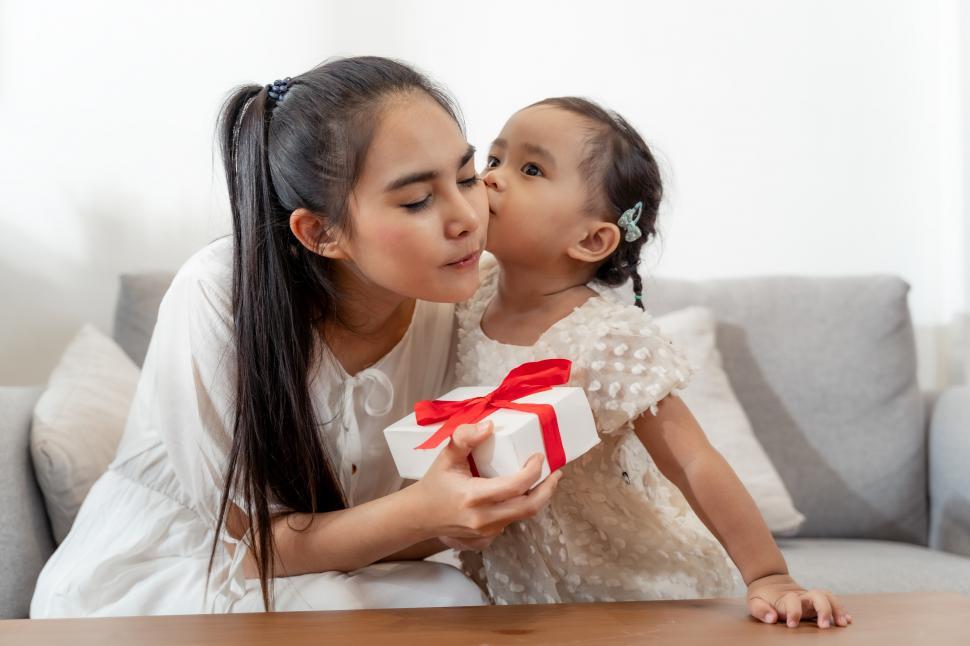 Free Image of Little pretty girl giving a gift to her happy mother 