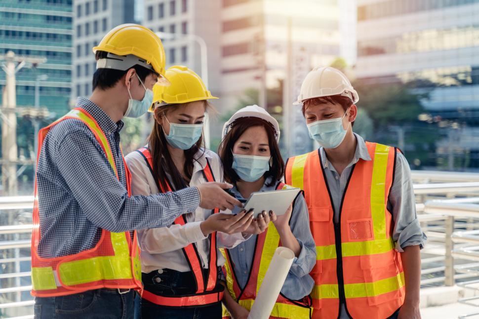 Free Image of Workers waring surgical mask and safety helmets on jobsite 