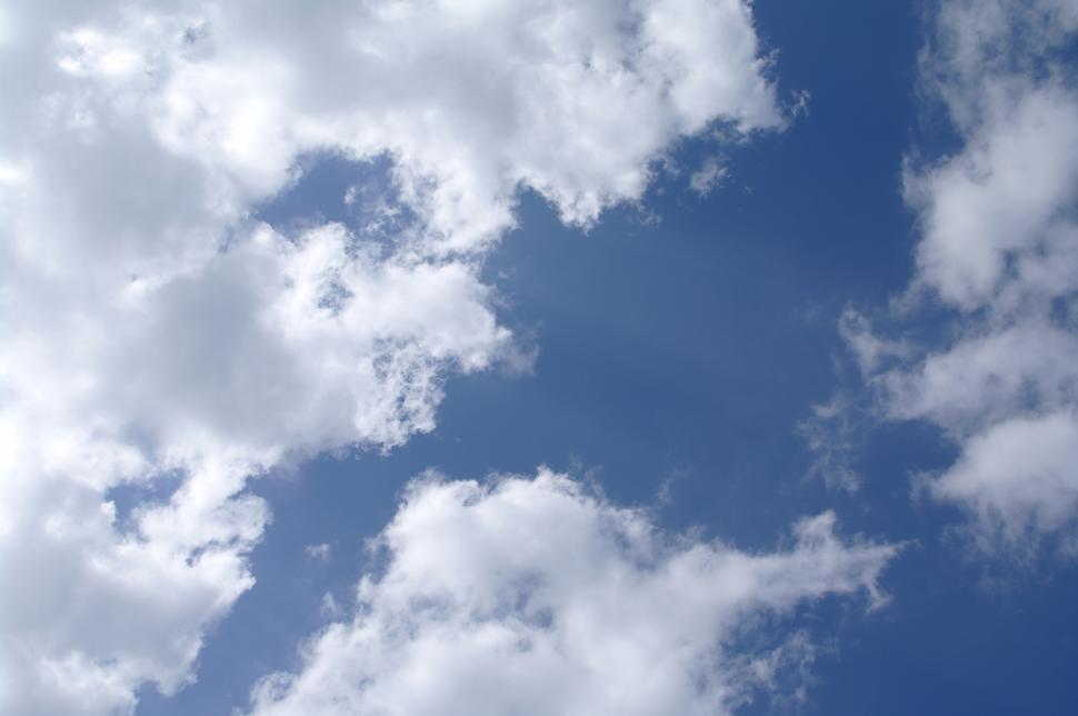 Free Image of A Plane Flying Through a Cloudy Blue Sky 