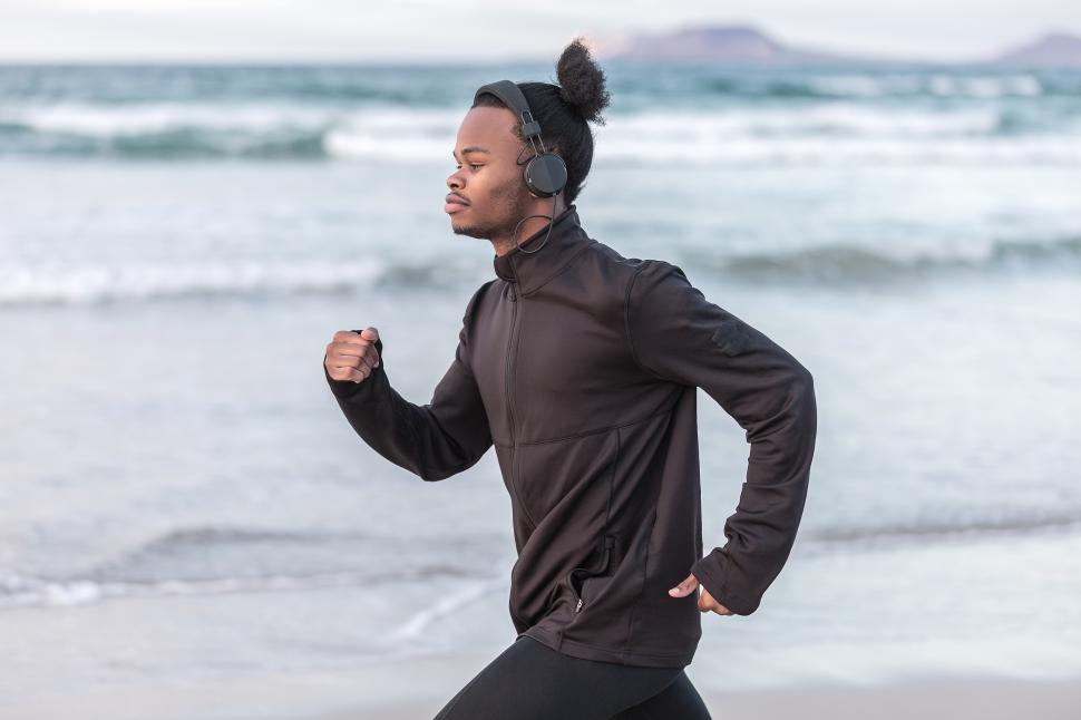 Free Image of Black man in headphones running near sea 