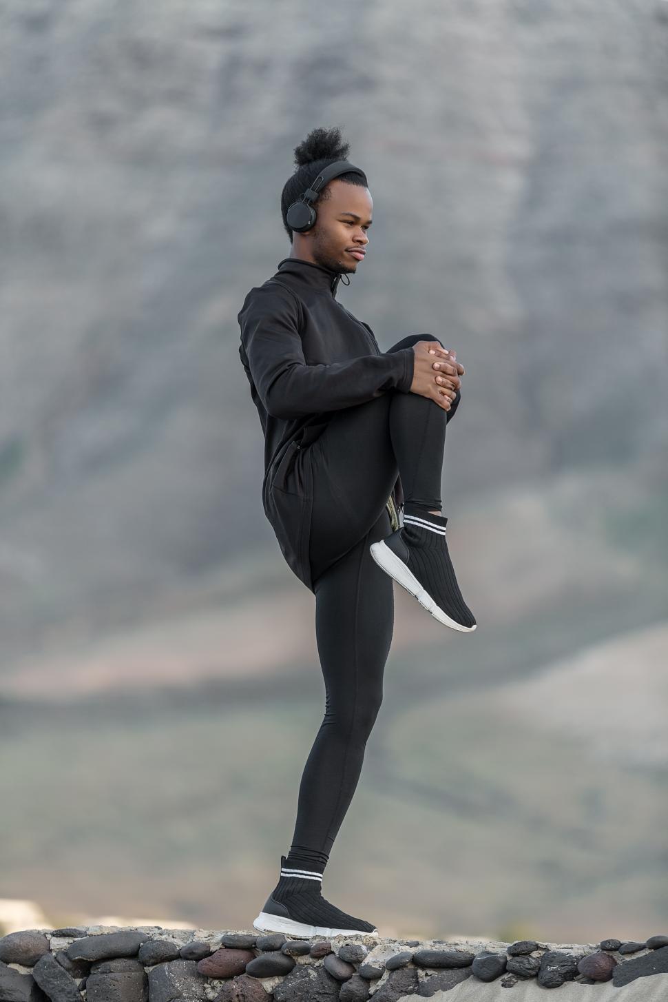 Free Image of Black athlete pulling leg to chest in nature 