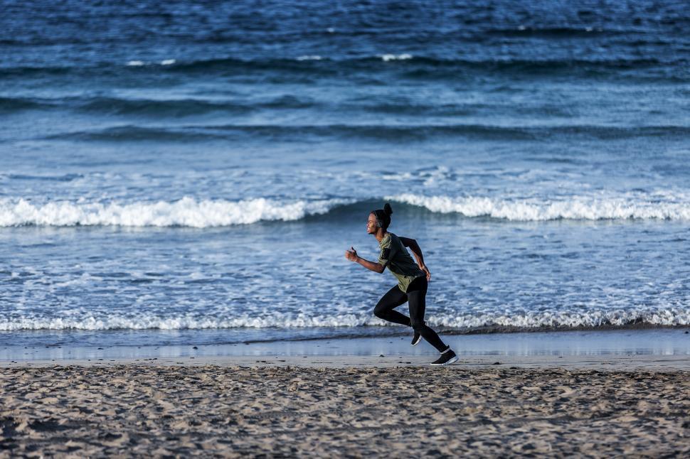 Free Image of Black man sprinting near waving sea 