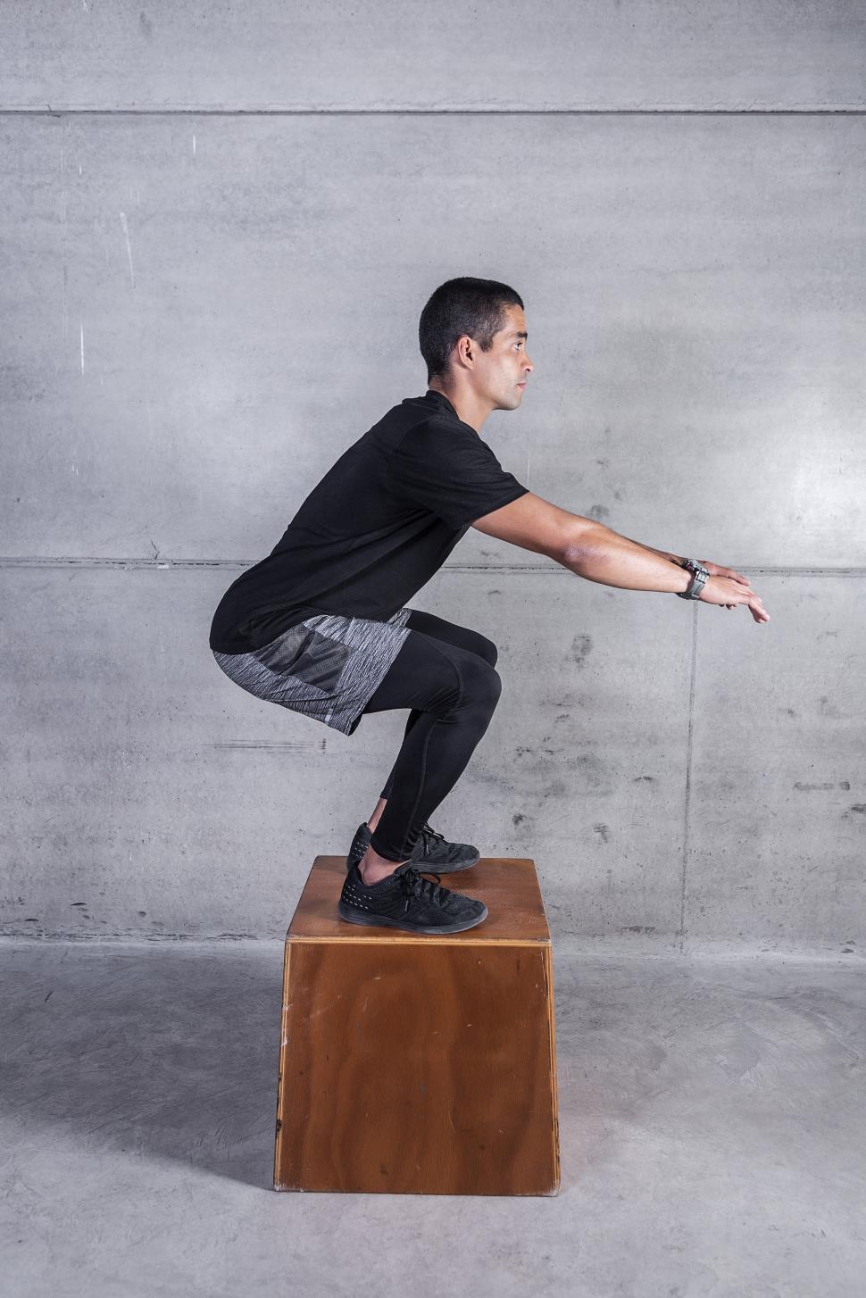 Free Image of Man squatting on wooden block 