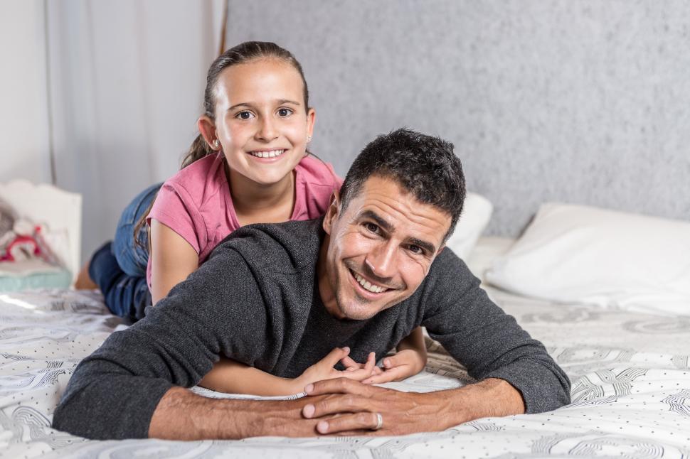Download Free Stock Photo of Father and daughter cuddling on bed 