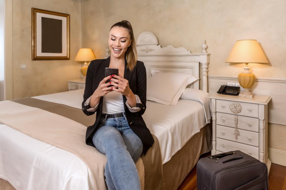Free Image of Happy young woman smiling using smartphone 