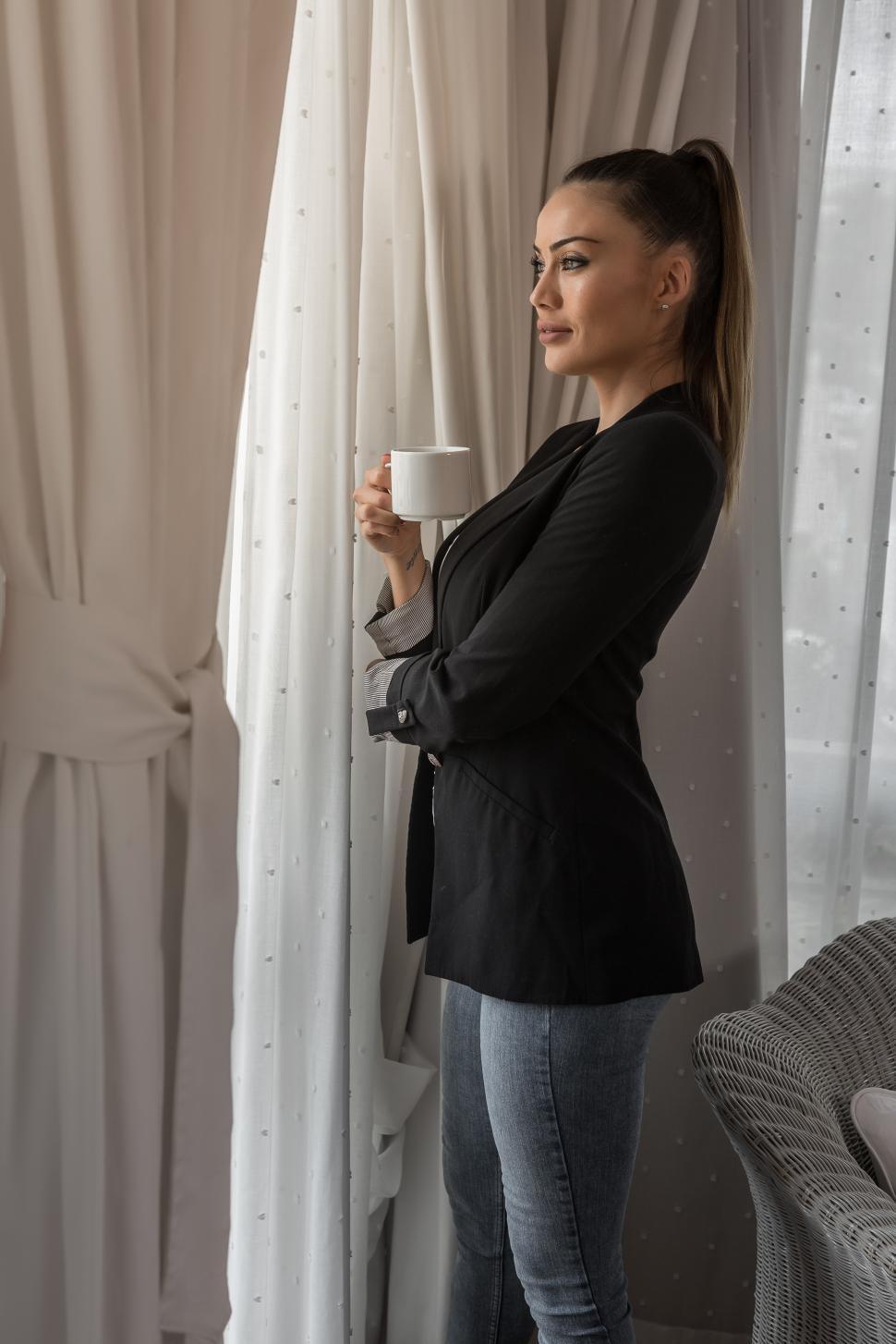 Free Image of Pensive young female standing with tea cup 