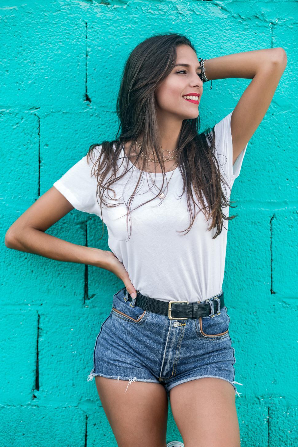 Free Image of Beautiful brunette female standing by turquoise wall 