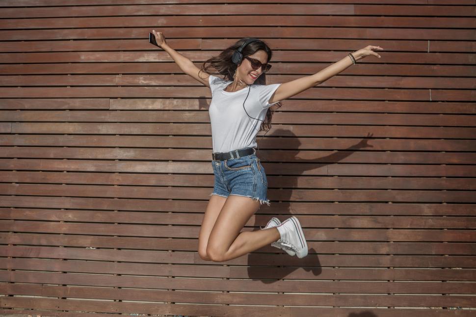 Download Free Stock Photo of Energetic woman jumping against wall 