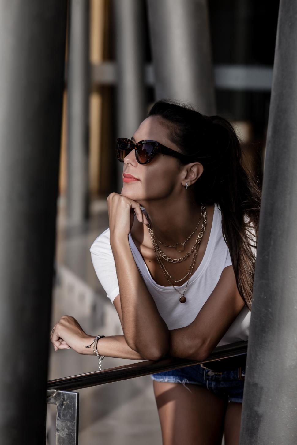 Free Image of Alluring woman in sunglasses resting while leaning on street han 