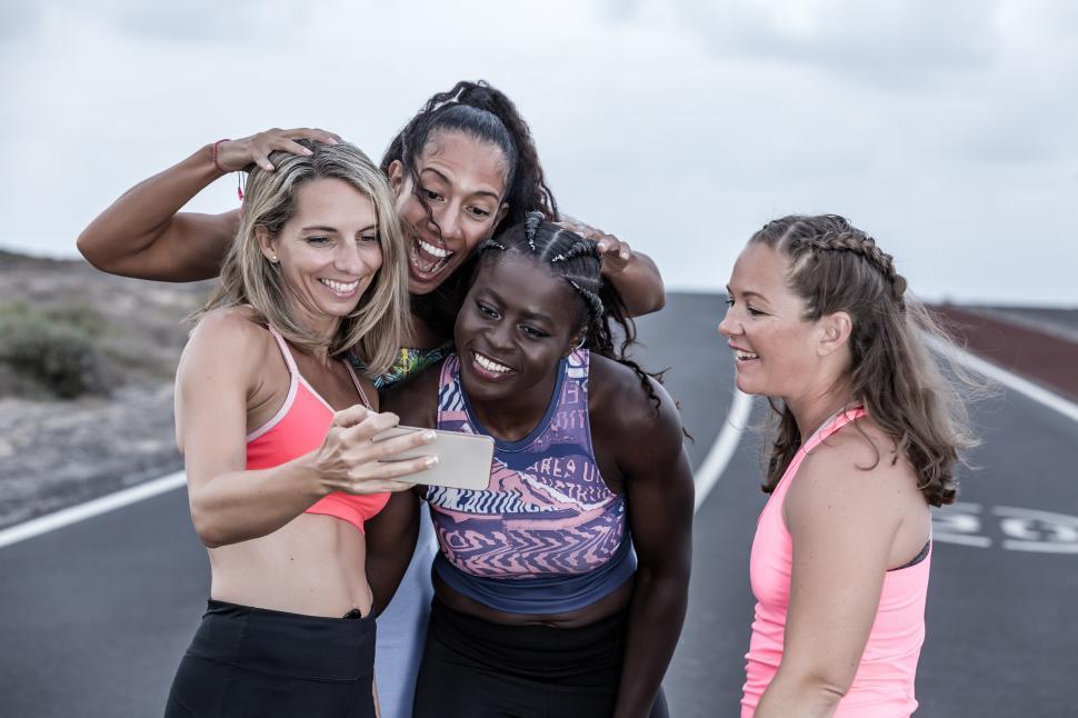 Free Image of Happy diverse sportswomen using smartphone together 