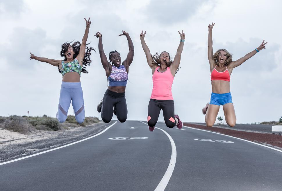 Free Image of Happy multiethnic female athletes jumping with raised arms 