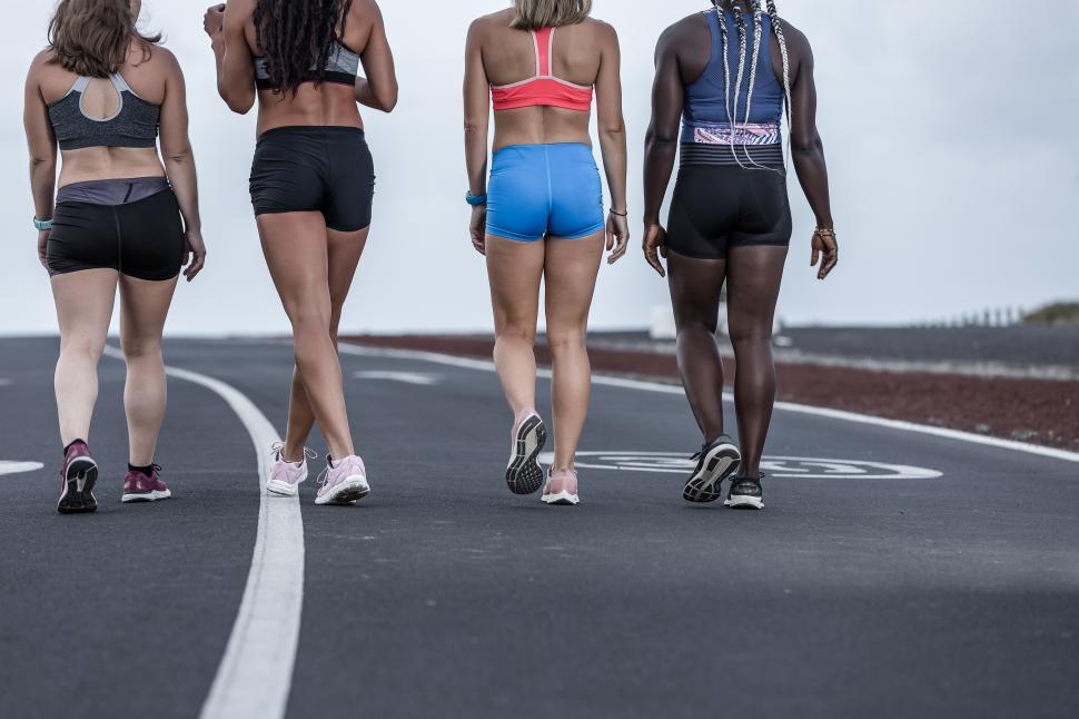 Free Image of Crop multiethnic sportswomen walking on road together 