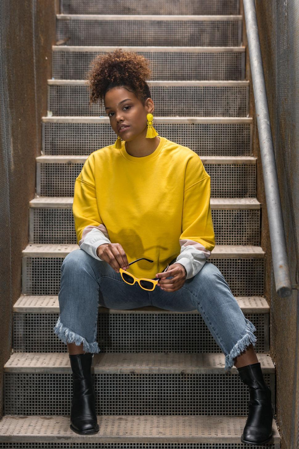 Free Image of Trendy black woman in yellow wear sitting on stairway 