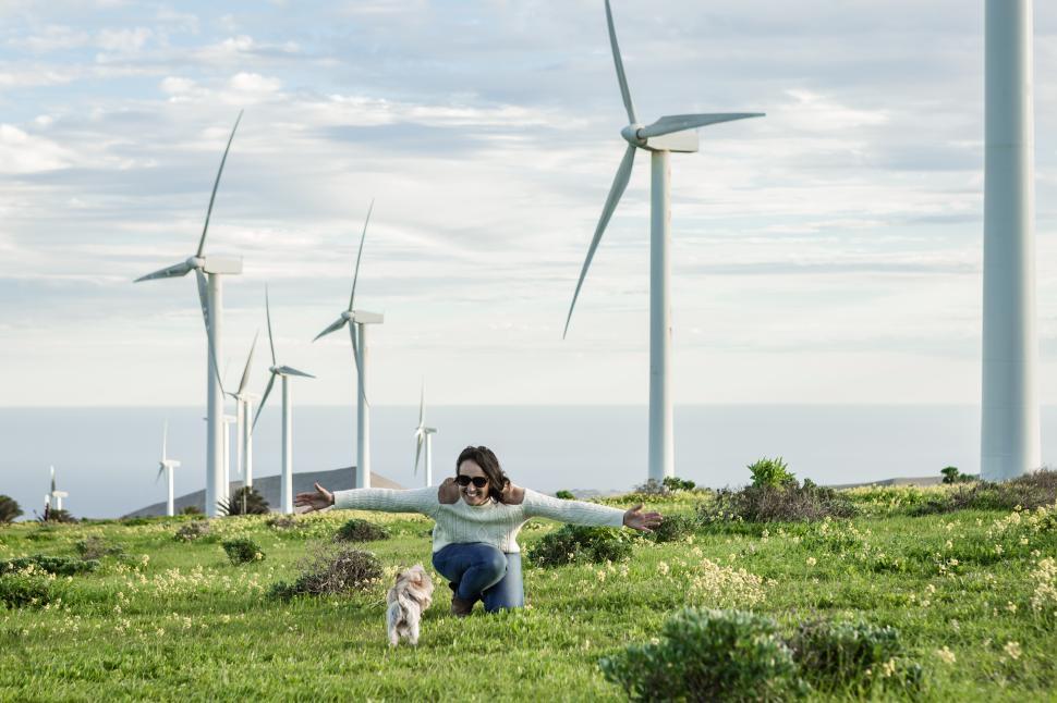Download Free Stock Photo of Smiling woman playing with dog in meadow with windmills 