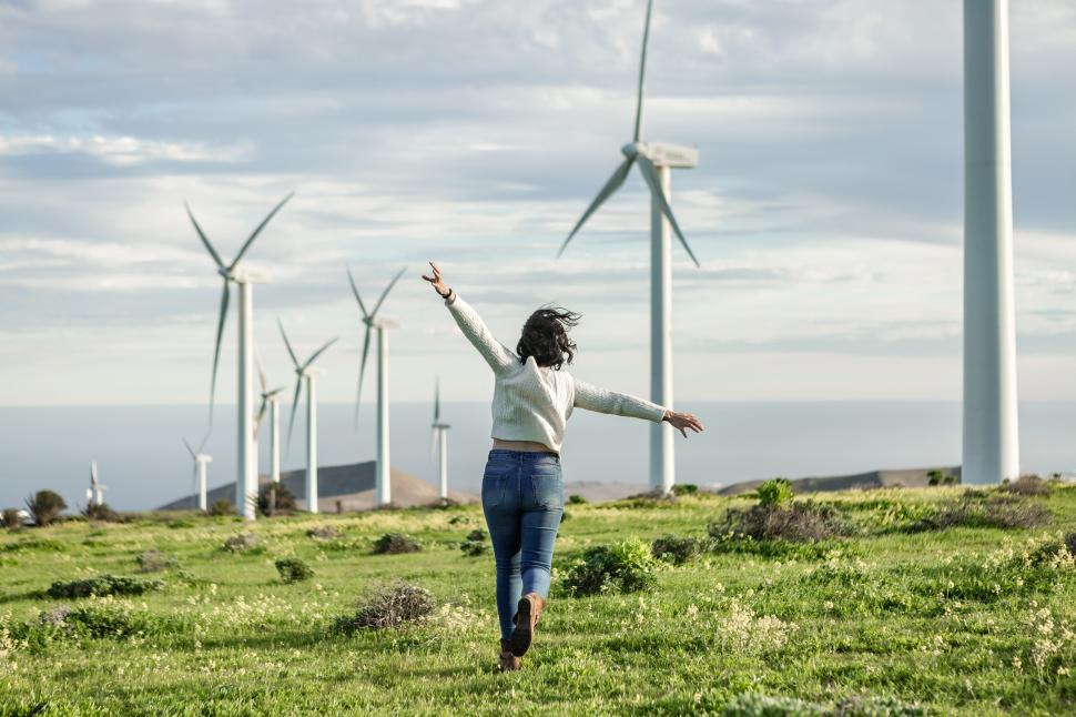 Download Free Stock Photo of Unrecognizable woman running in meadow with windmills 