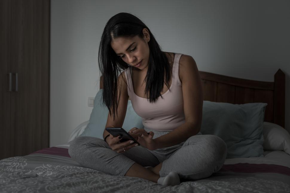 Free Image of Woman browsing smartphone on bed 
