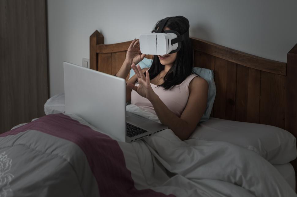 Free Image of Woman experiencing virtual reality on bed at home 