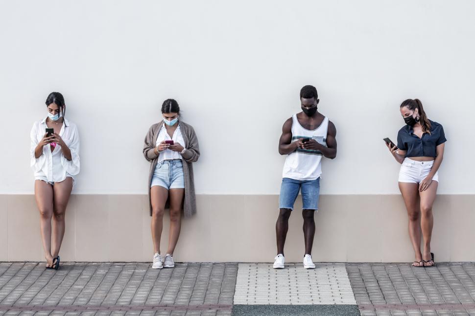 Free Image of Diverse friends browsing smartphones on street 