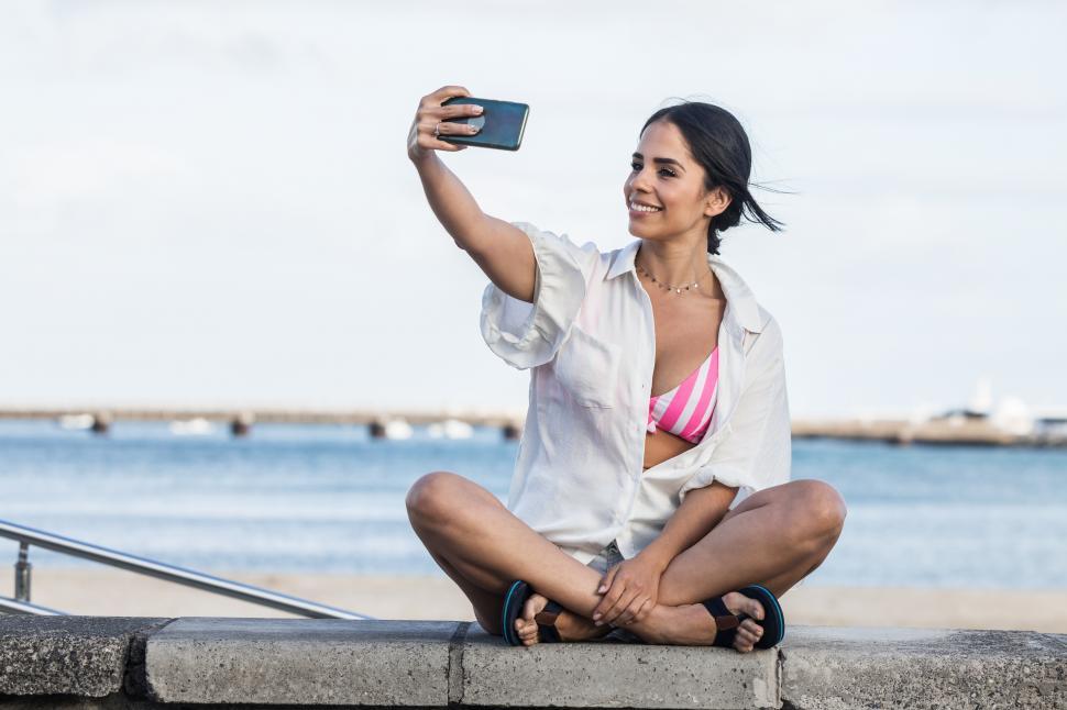Free Image of Happy woman taking self portrait at seaside 