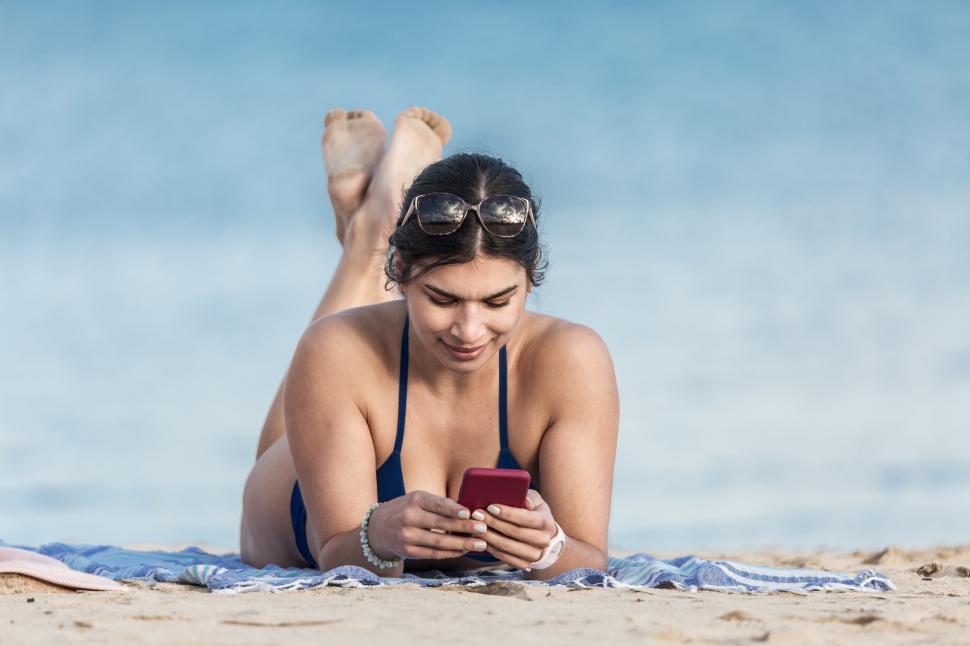 Free Image of Woman using smartphone on beach 