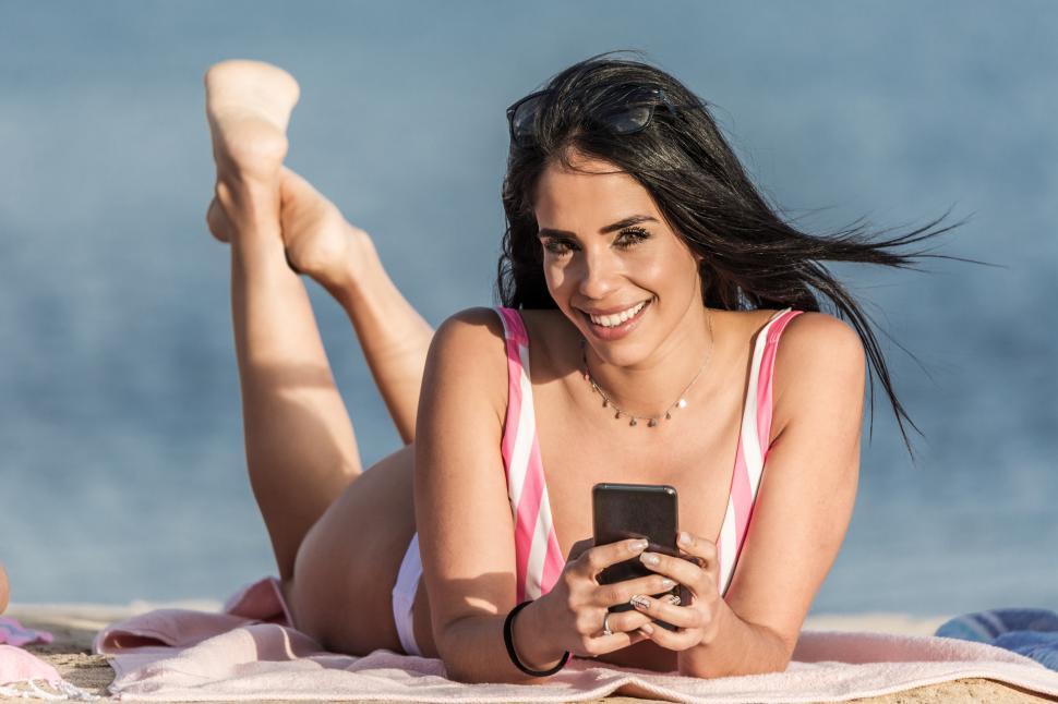Free Image of Happy woman with smartphone relaxing on beach 